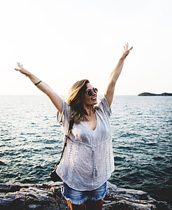 woman raising two arms near water thumbnail