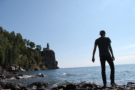 man standing on rack near body of water during daytime thumbnail
