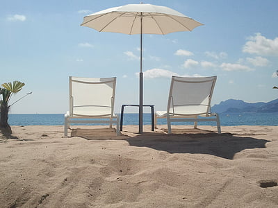 white lounge chairs on seashore thumbnail