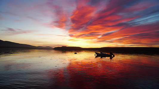 canoe floating on lake under cloudy sky thumbnail