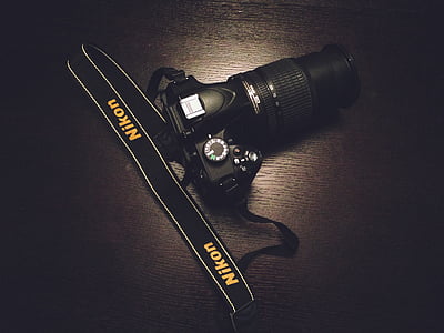 black Nikon DSLR camera on brown wooden surface thumbnail