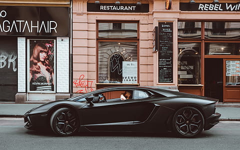 photo of person in black sports car beside restaurant thumbnail