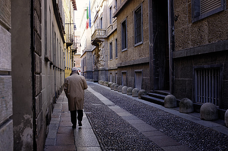 person walking near gray buildings thumbnail