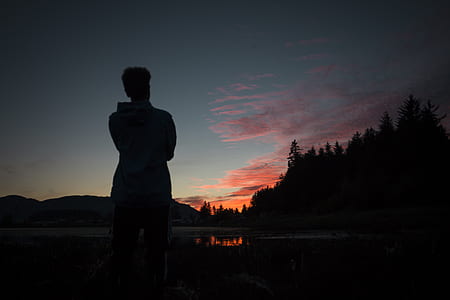 person standing near fire pit under golden hour silhouette thumbnail