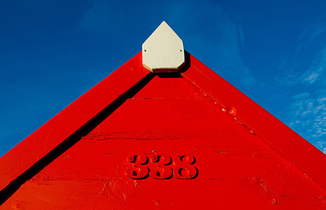 A red coastal hut contrasts against a blue sky thumbnail