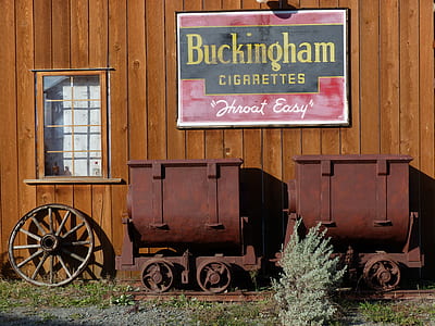 Buckingham Cigarettes sign above brown train parked beside wall at daytime thumbnail