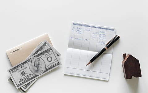 black click pen on passbook beside 100 U.S. dollar banknote thumbnail
