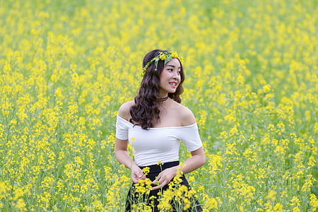 selective focus portrait photograph of woman wearing white off-shoulder dress on a bed of yellow petaled flowers thumbnail