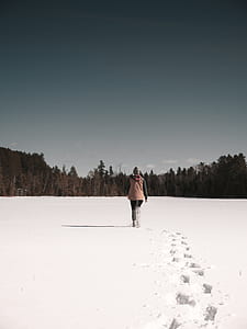 person walking on snow fields during daytime thumbnail