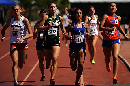 women wearing tank tops running on brown running track during daytime thumbnail