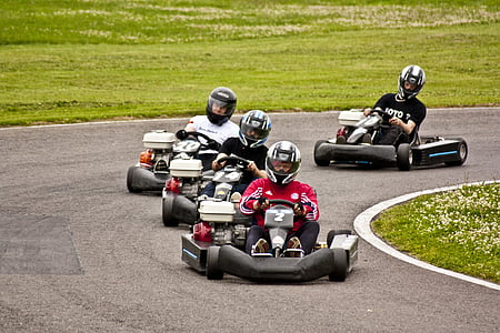 four men riding go-kart on road thumbnail