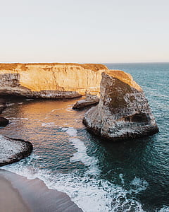 seashore near rock cliff during daytime thumbnail