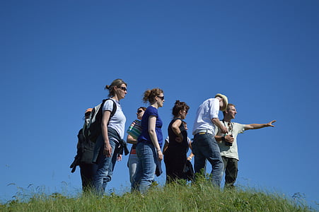 group of people standing on green grass field under blue sky thumbnail