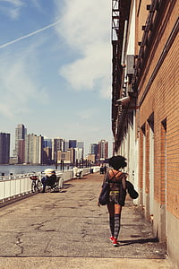 woman walking beside building under surveillance camera thumbnail