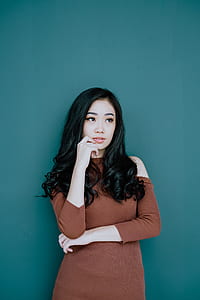 woman holding lips while standing beside green wall thumbnail