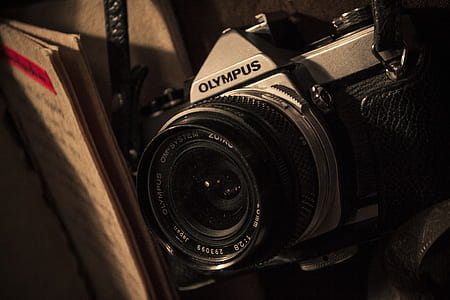 gray Olympus camera beside book thumbnail
