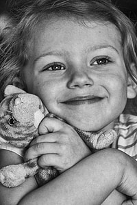 grayscale photo of girl hugging plush toy thumbnail