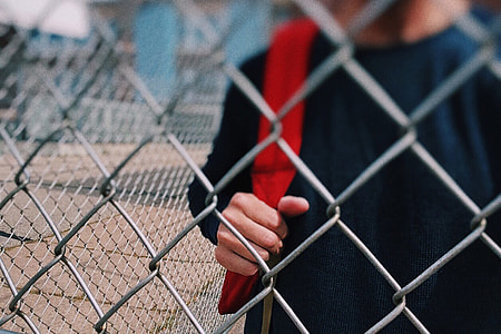 Child by fence in school playground thumbnail
