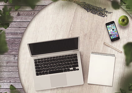grey laptop computer near notebook page on round brown wooden table thumbnail