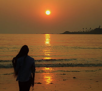woman standing near shore during golden hour thumbnail
