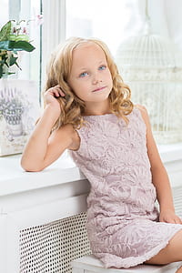 girl wearing purple floral boat-neck sleeveless dress sitting on white wooden bench thumbnail