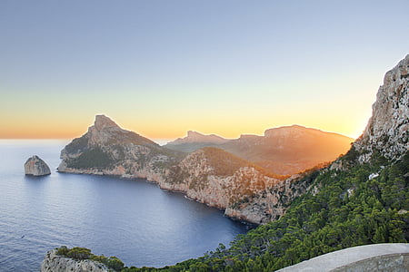 body of water across mountain during daytime thumbnail