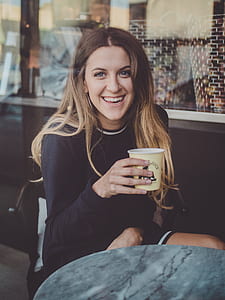 woman sitting on chair while holding coffee cup thumbnail