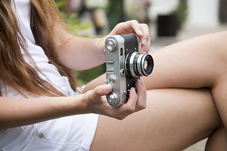 woman wearing white top holding camera thumbnail