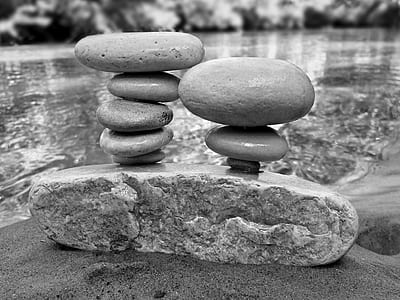 grayscale photo of stones stacked on top of rock thumbnail