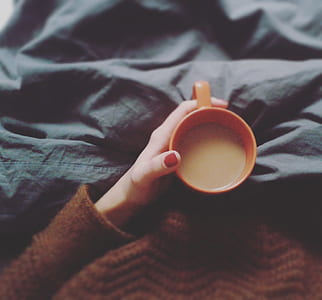 person holding orange mug filled with brown liquid thumbnail
