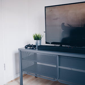flat screen TV on gray wooden TV stand inside room thumbnail