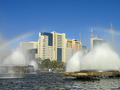 turned-on water fountains in front of white concrete high-rise buildings thumbnail
