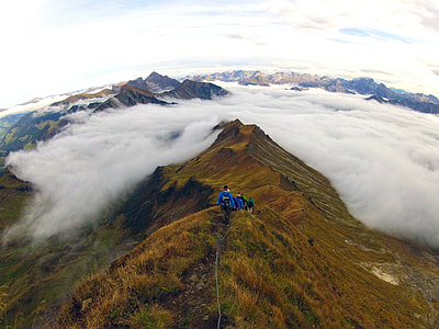 landscape photography of people hiking mountain peaks under white cloud blue skies thumbnail