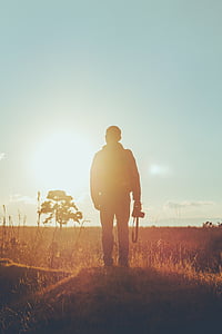 silhouette of man holding camera standing on grass field thumbnail