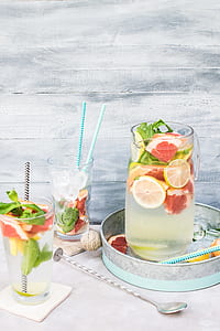 sliced lemon on clear glass pitcher near drinking glasses thumbnail