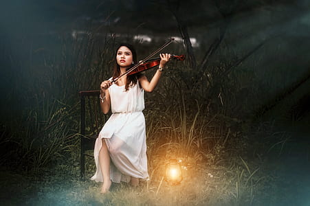 woman in white scoop-neck sleeveless dress holding brown violin thumbnail