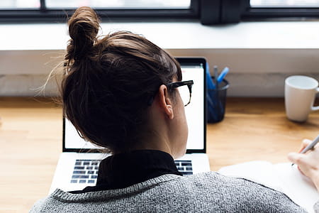 Female Taking Notes And Browsing Laptop Photo thumbnail