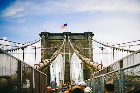 view of Brooklyn bridge with US flag on top thumbnail