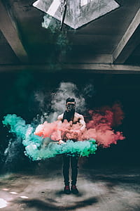 man covering his eye holding red and green smoke inside the building thumbnail