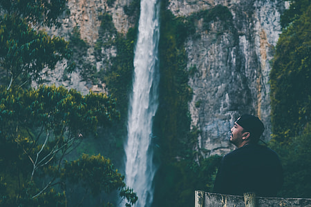 man sitting in front of waterfalls thumbnail