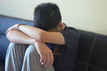 boy wearing gray sweatpants sitting on black leather couch thumbnail