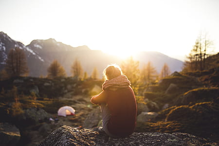 photo of man sitting on stone during daytime thumbnail