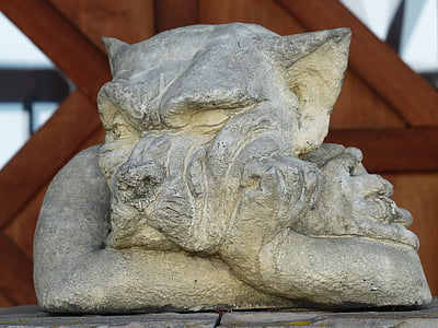 gray gargoyle statue leaning beside brown wall thumbnail