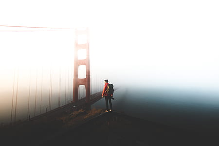 person standing on cliff near golden gate bridge at cloudy sky during daytime thumbnail