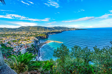 aerial view photography of village near beach and mountain range under calming sky thumbnail