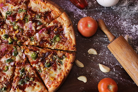 sliced pizza beside rolling pin and tomatoes thumbnail