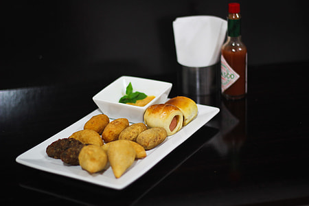 baked pastries on plate besides hot sauce bottle thumbnail