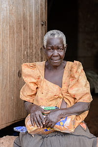 Photo of a Woman Sitting Near a Wooden Door thumbnail