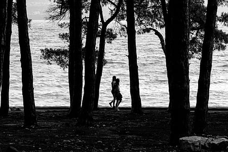 silhouette photography of two person walking near body of water thumbnail