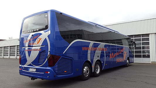 blue and black bus parked near white wooden building at daytime thumbnail